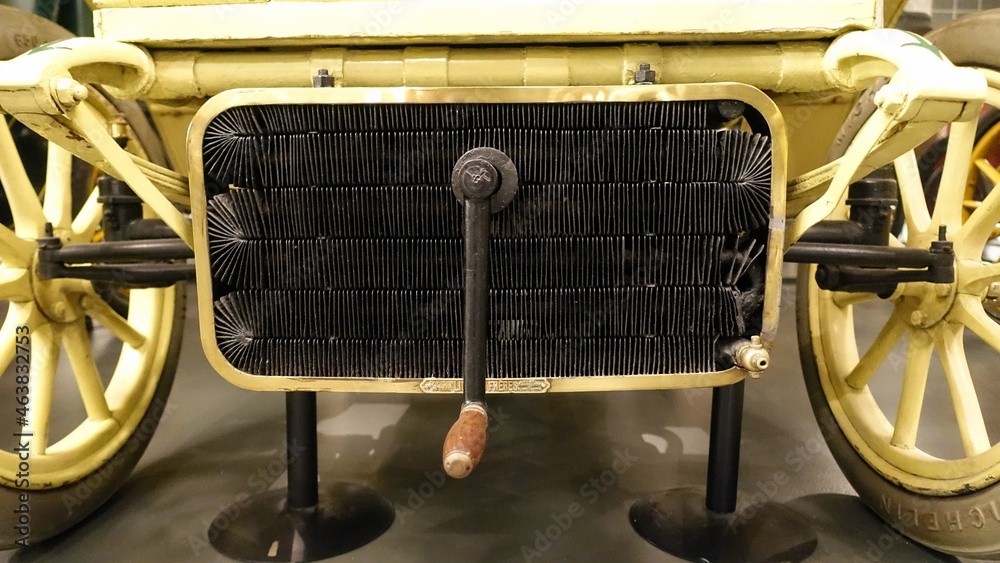 a view of a radiator and a crank of an antique car 