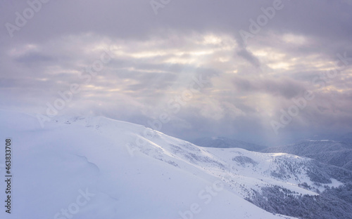 Snow covered slopes under a cloudy sky. © Oleksiy