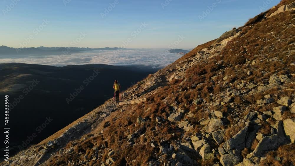 lady climbing to the dawn, on one level up the mountain, objective the highest point. fit young lady with divider pieces, behind amazing mountain scene