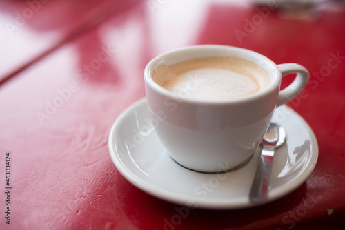 Coffee cream in shiny white cup on red wooden table. Close up of a milk coffee with space for text. photo