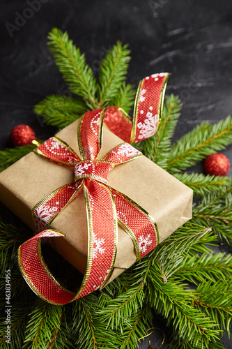 Gift box with Christmas tree branch and red balls on black