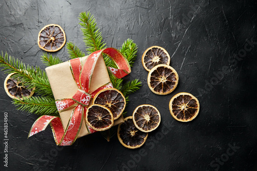 Christmas gift box and gree fir tree branches with dried orange fruit top view
