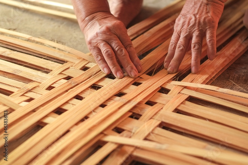 Hand elderly woman are weave bamboo strips of bottom of basket bamboo close-up.