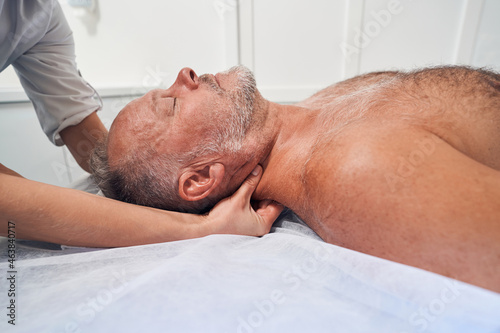 Man receiving professional neck massage in spa salon