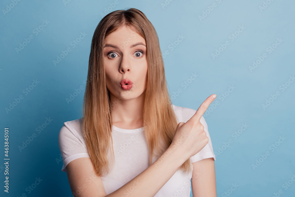 Photo of excited amazed shocked lady direct forefinger empty space omg reaction on blue color background Photo of excited amazed shocked lady direct forefinger empty space omg reaction on blue color background