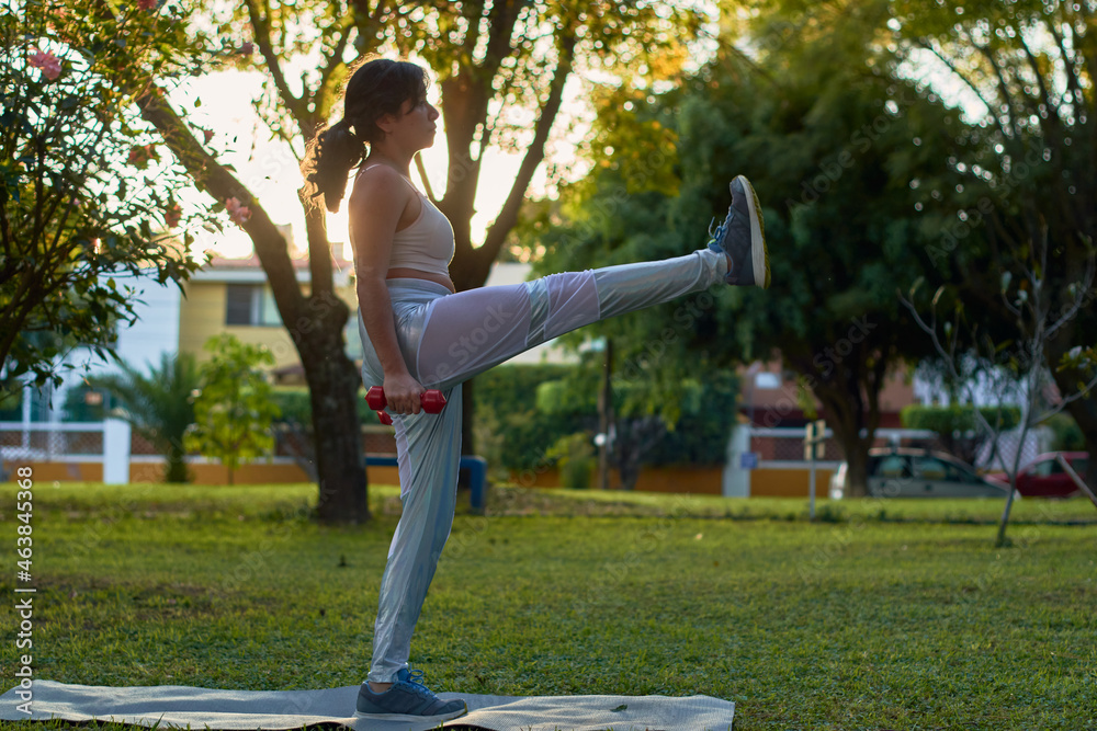 Young latina woman exercises with dumbbells in park. Young latina woman exercises with dumbbells in park.