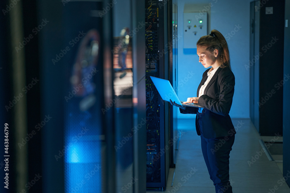 Female engineer working in server room at modern data center - obrazy, fototapety, plakaty 