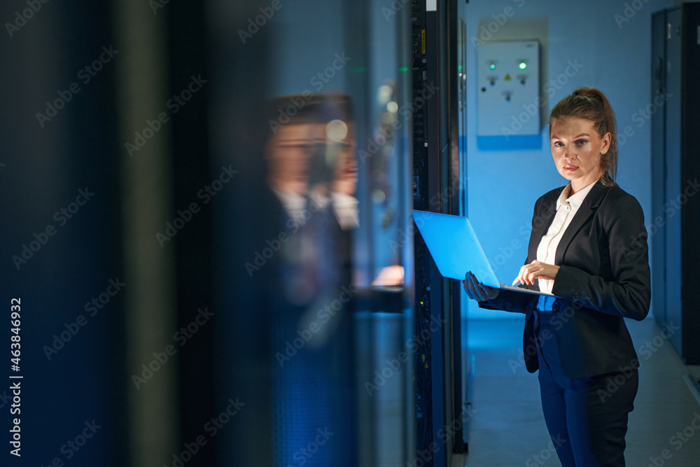 Female IT professional working in server room with laptop Female IT professional working in server room with laptop