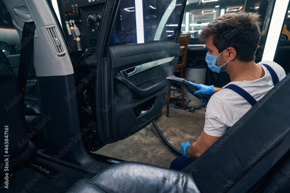 Specialist doing steam cleaning to handle of car side door Specialist doing steam cleaning to handle of car side door