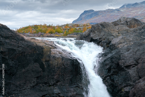 Closeup  wide  low angle shot of mighty Stuor Muorkkegarttje waterfall on Lulealven river on a cloudy day of arctic autumn. Stora Sjofallet national park  Sweden.