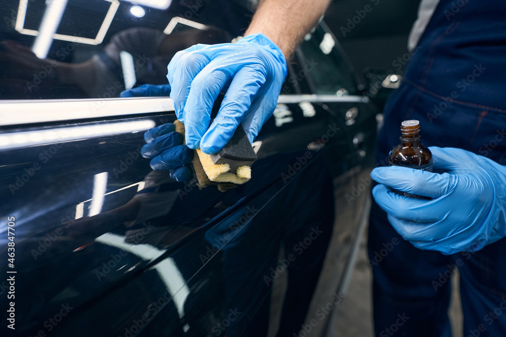 Worker with microfiber applicator spreading ceramic coating on car Worker with microfiber applicator spreading ceramic coating on car