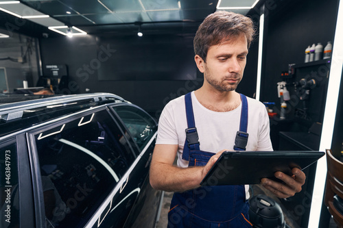Auto repairman is checking information on tablet