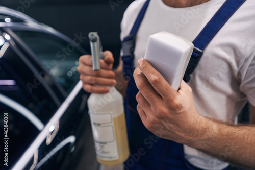 White sponge in hand of man in car repair workshop