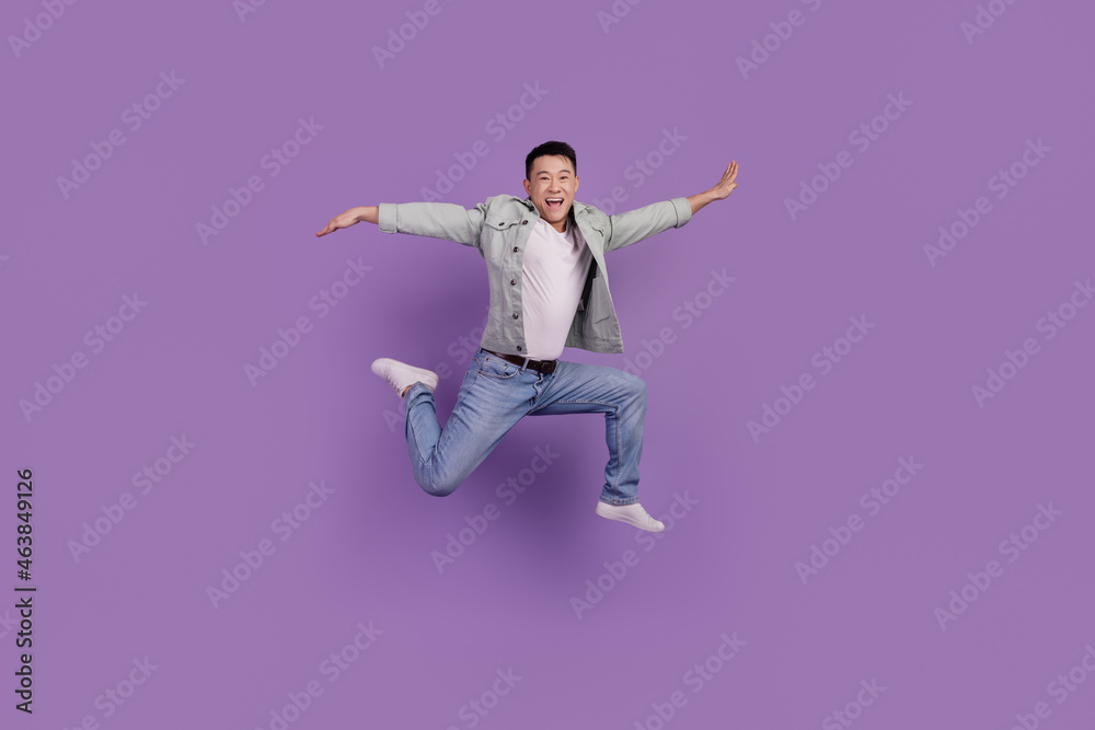 Photo of sporty chinese man jump run fast hurry rush isolated violet color background