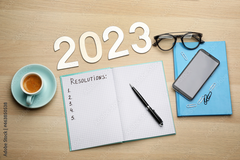 Making resolutions for 2023 new year. Flat lay composition with notebook on wooden table Making resolutions for 2023 new year. Flat lay composition with notebook on wooden table
