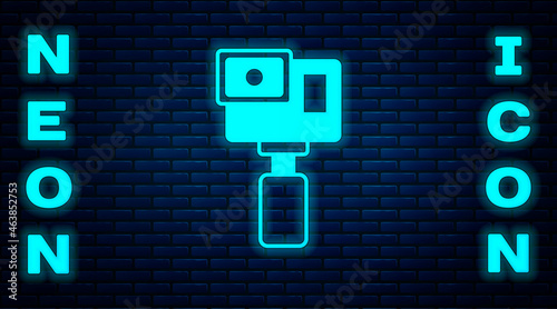 Glowing neon Action extreme camera icon isolated on brick wall background. Video camera equipment for filming extreme sports. Vector