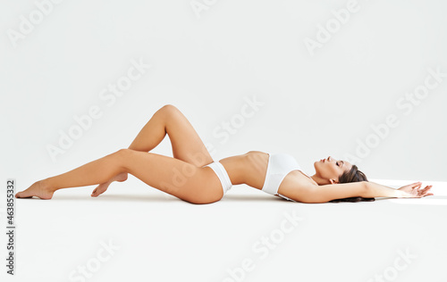 Sexy sporty woman in white lingerie posing lying on floor. Full length portrait