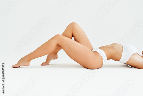 Slim tanned woman's legs on white studio background