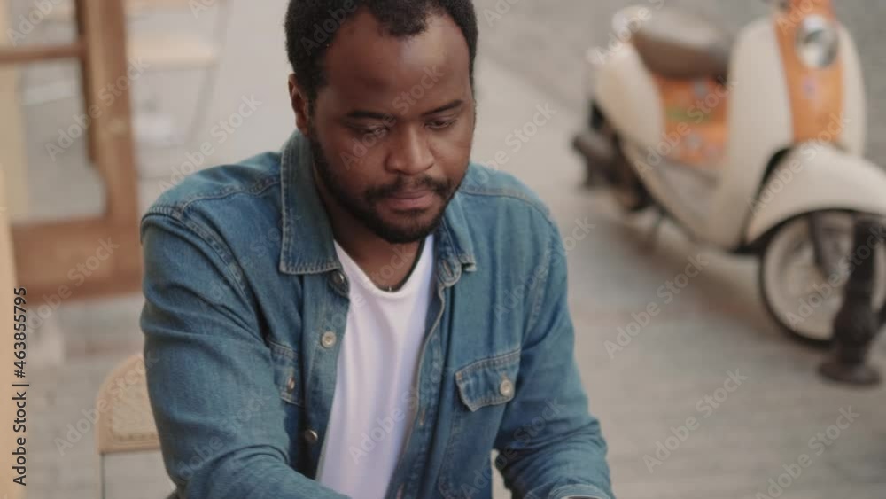 Close-up view of pensive African man writing in cafe outdoors Close-up view of pensive African man writing in cafe outdoors