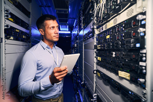 Concentrated tranquil system administrator inspecting networking equipment photo