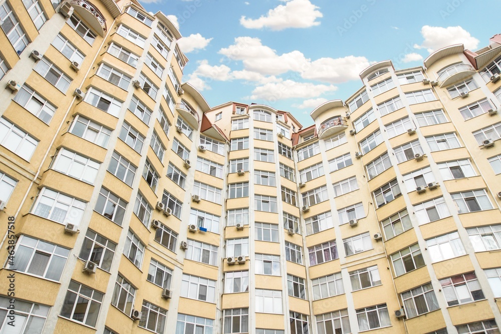 Fototapeta premium Fragment of Modern residential apartment with flat buildings exterior. Detail of New luxury house and home complex. Part of City Real estate property and condo architecture. Copy space. Blue sky