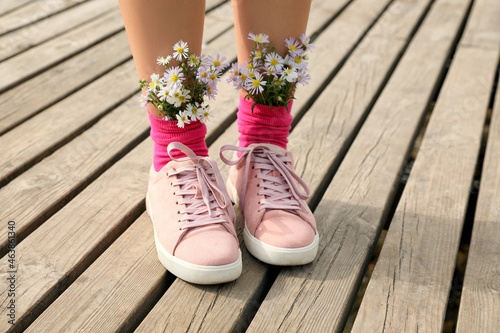 Woman with beautiful tender flowers in socks on wooden pier, closeup photo