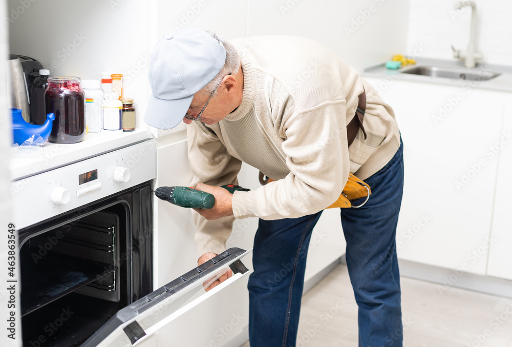 Technician or plumber repairing the dishwasher in a household Technician or plumber repairing the dishwasher in a household