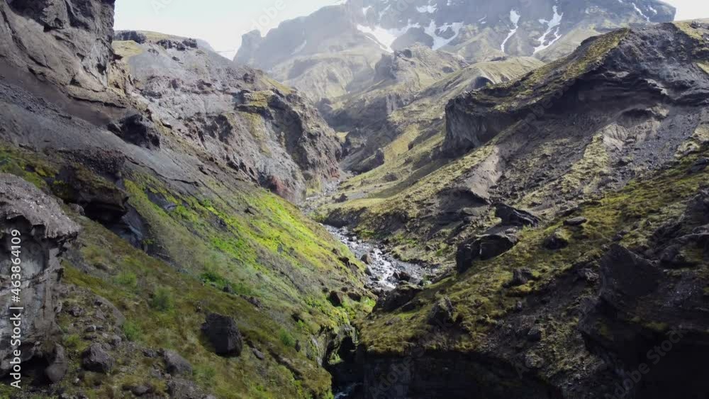 Aerial shot of a narrow ravine revealing a stream flowing on the rocks alongside cliffs. Canyon walking in Iceland. Aerial shot of a narrow ravine revealing a stream flowing on the rocks alongside cliffs. Canyon walking in Iceland.
