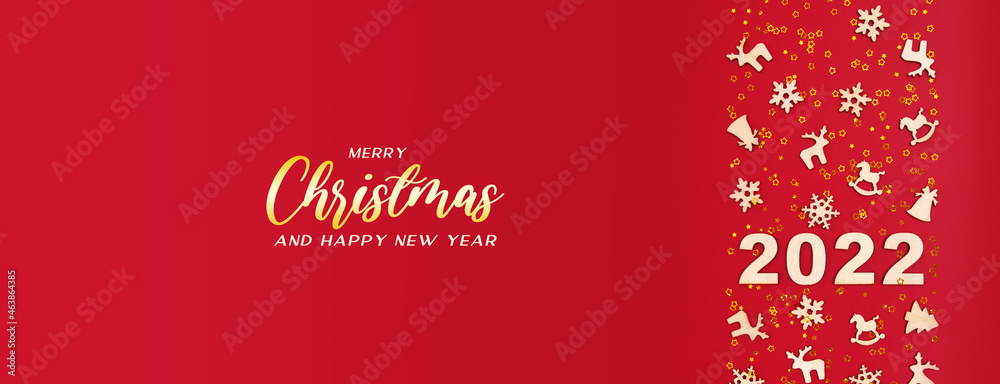 Greting Merry Chtistmas and 2022 Happy New year on red background with golden stars and Cristmas wood decorations