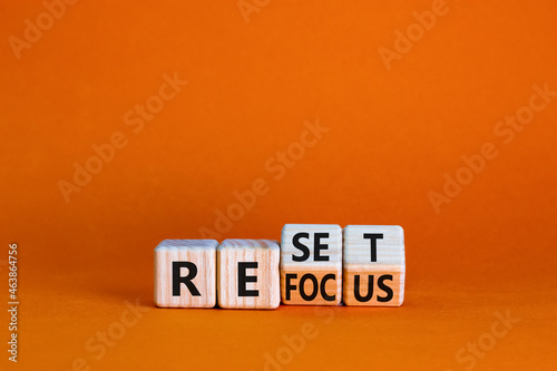 Refocus and reset symbol. Businessman turned cubes and changed the word 'refocus' to 'reset'. Beautiful orange table, orange background. Business refocus and reset concept. Copy space.