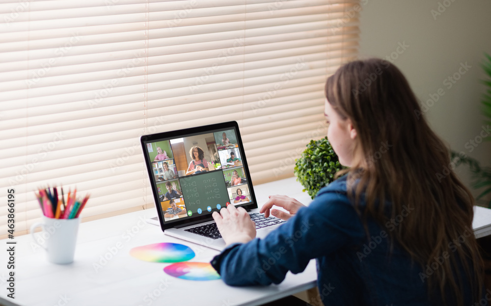 Fototapeta premium Caucasian girl using laptop for video call, with smiling diverse elementary school pupils on screen