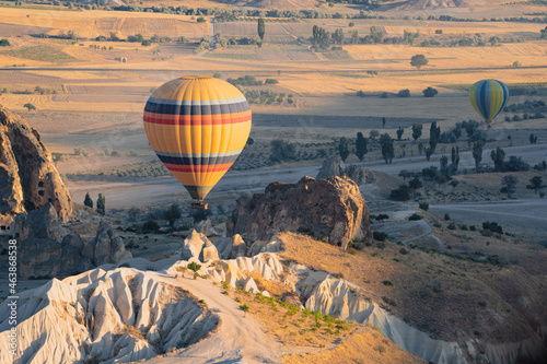 hot air balloon with rainbow colors pattern rising over the Cappadocian valley