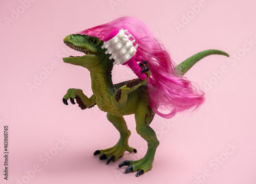 Dinosaur with long curly pink hair is holding  comb. Beauty salon. Humor concept about caring for curly hair. © dvulikaia