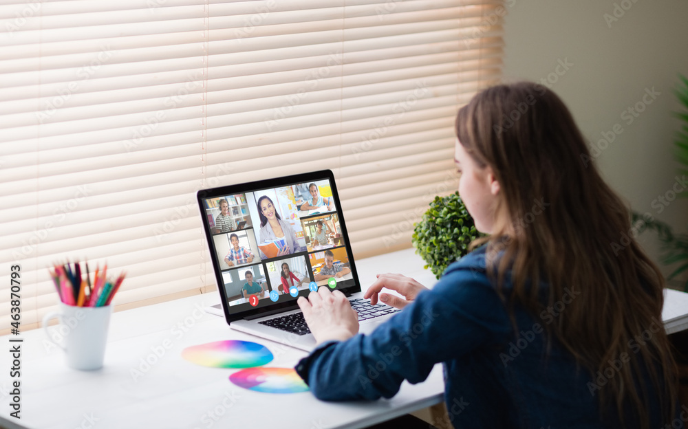 Caucasian woman using laptop for video call, with smiling diverse elementary school pupils on screen Caucasian woman using laptop for video call, with smiling diverse elementary school pupils on screen