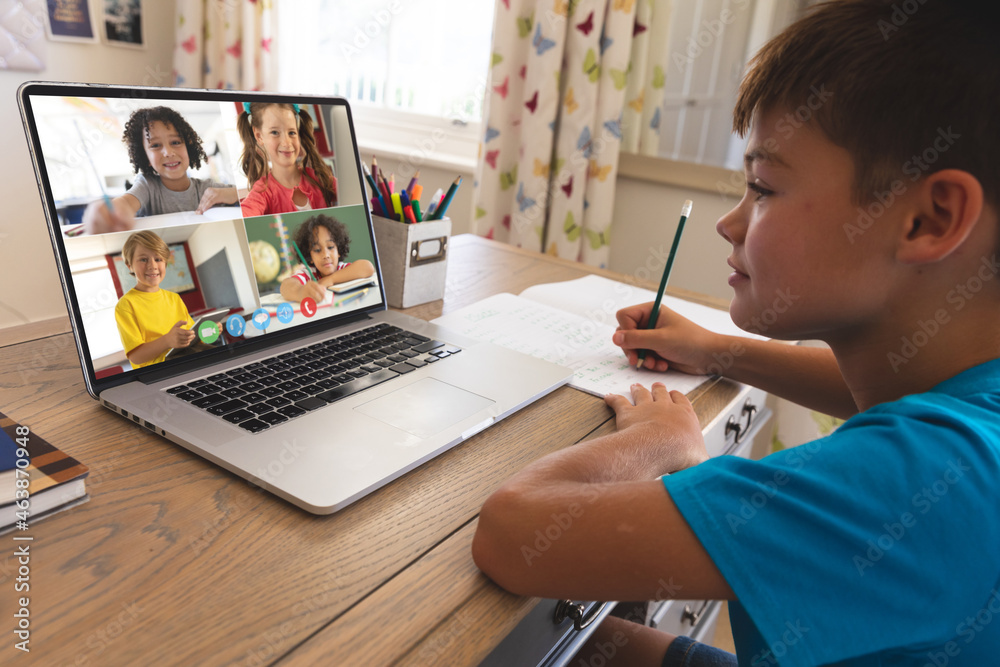 Smiling caucasian boy using laptop for video call, with diverse elementary school pupils on screen Smiling caucasian boy using laptop for video call, with diverse elementary school pupils on screen