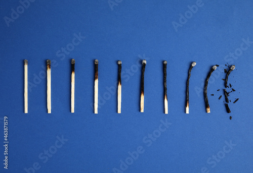 Different stages of burnt matches on blue background  flat lay