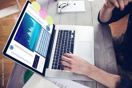 Hands of caucasian businessman sitting at desk using laptop with statistical data on screen photo