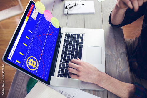 Hands of caucasian businessman sitting at desk using laptop with statistical data on screen photo