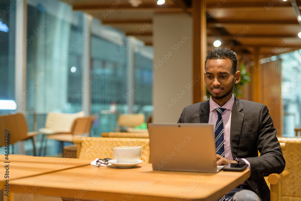 Young African businessman in coffee shop using laptop computer