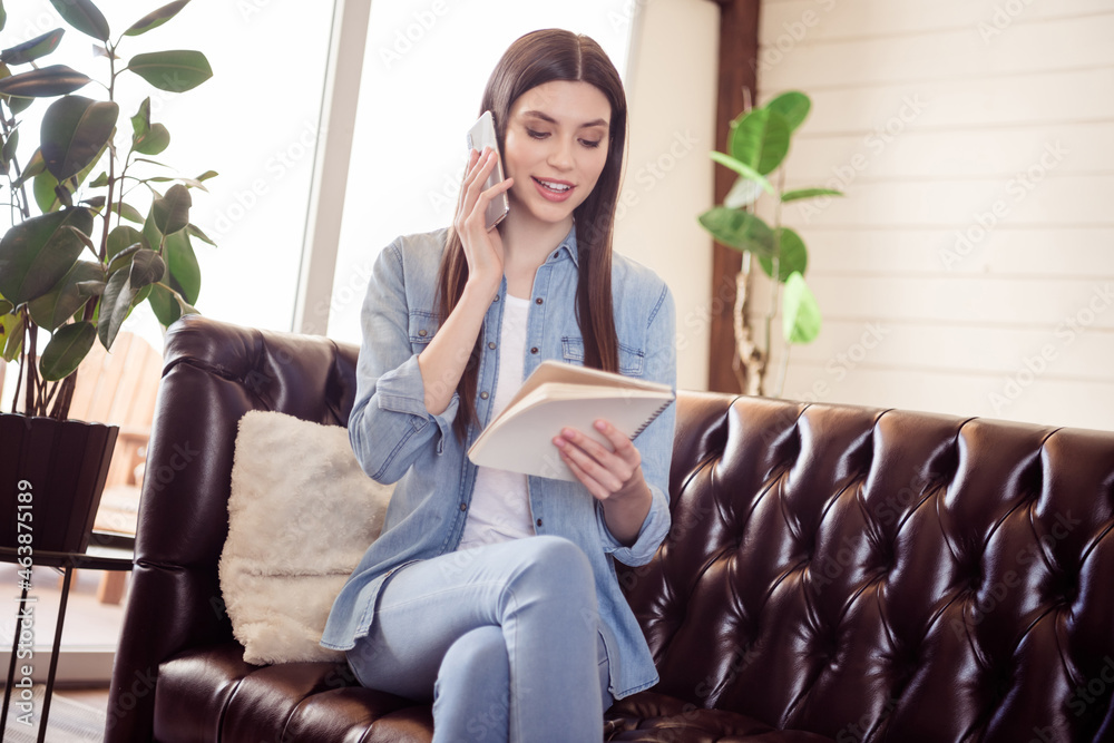 Obraz premium Photo of charming cheerful young happy woman hold notebook read talk phone indoors inside house home