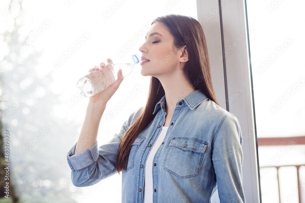 Profile side photo of young attractive woman happy positive smile enjoy drink water bottle hydration fresh indoors Profile side photo of young attractive woman happy positive smile enjoy drink water bottle hydration fresh indoors