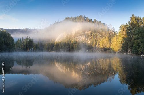 Beautiful colored trees with lake in autumn, landscape photography. Late autumn and early winter period. Outdoor and nature. Amazing foggy morning. Lake coast. Fog over autumn lake water. © Michal