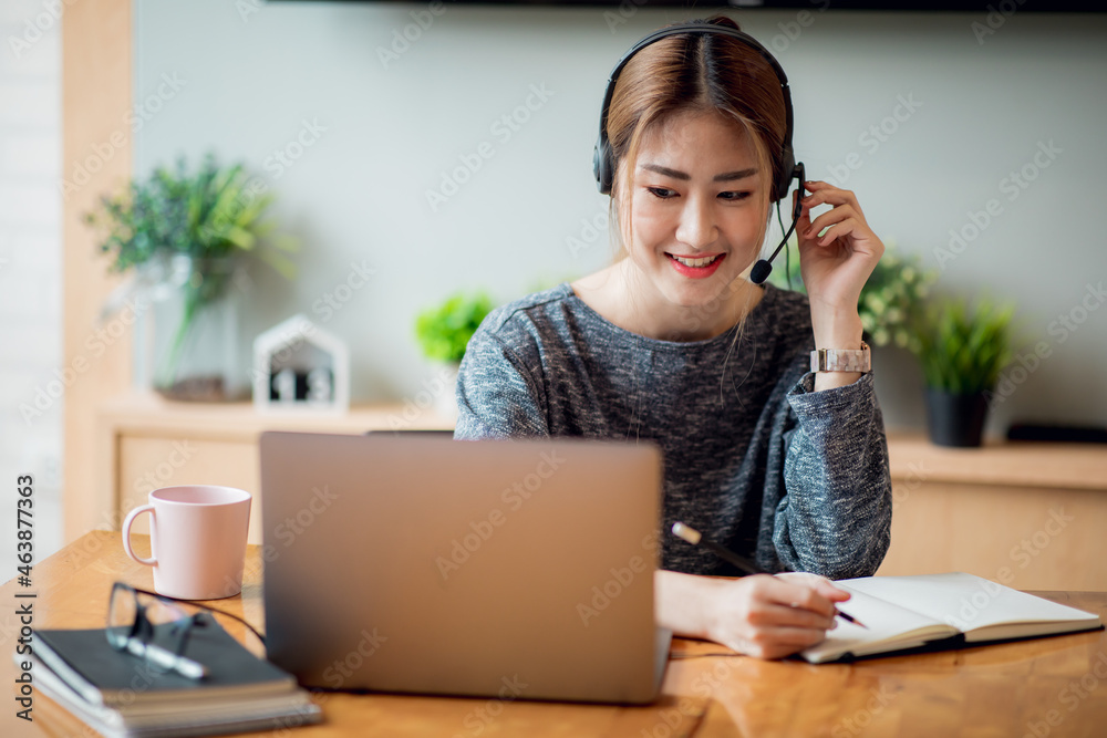 Young attractive university student using a laptop computer, studying online at home. Cheerful caucasian asian woman writes notes, planning working process, sitting at home. Exam preparation. Young attractive university student using a laptop computer, studying online at home. Cheerful caucasian asian woman writes notes, planning working process, sitting at home. Exam preparation.