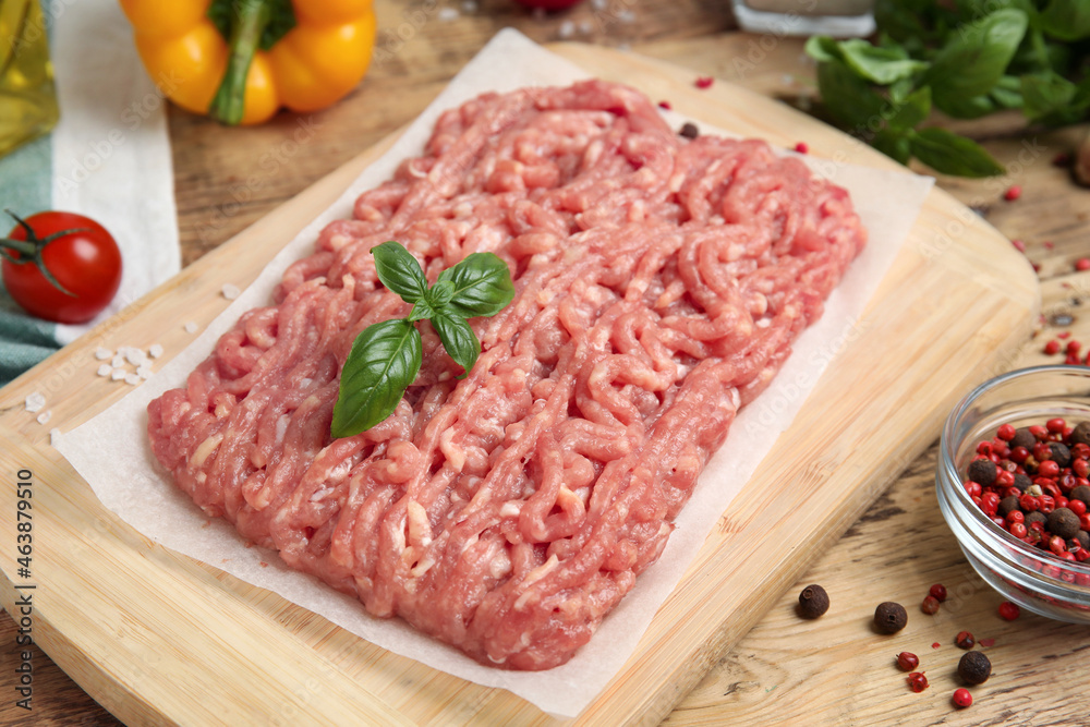 Raw chicken minced meat with basil and spices on wooden table, closeup Raw chicken minced meat with basil and spices on wooden table, closeup