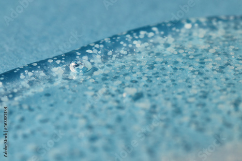 Texture of transparent gel with polishing beads on blue.
