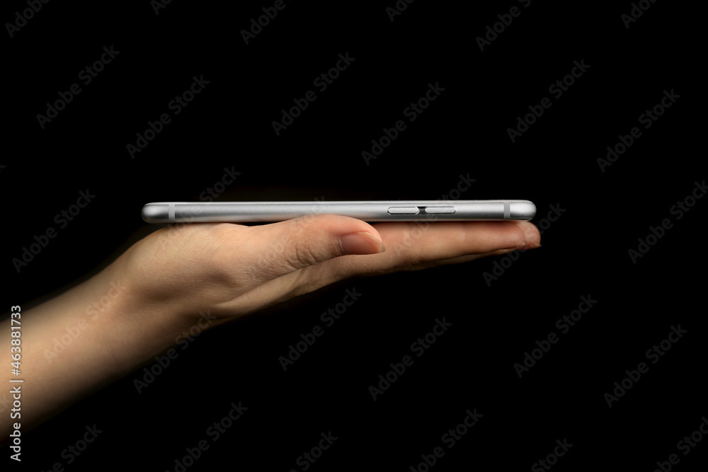 Hand holding mobile phone side view for presenation, studio shot, template or mockup on a black background photo Hand holding mobile phone side view for presenation, studio shot, template or mockup on a black background photo
