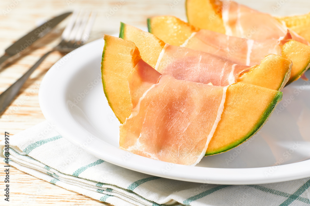 Cantaloupe melon and prosciutto ham on a ceramic bowl.