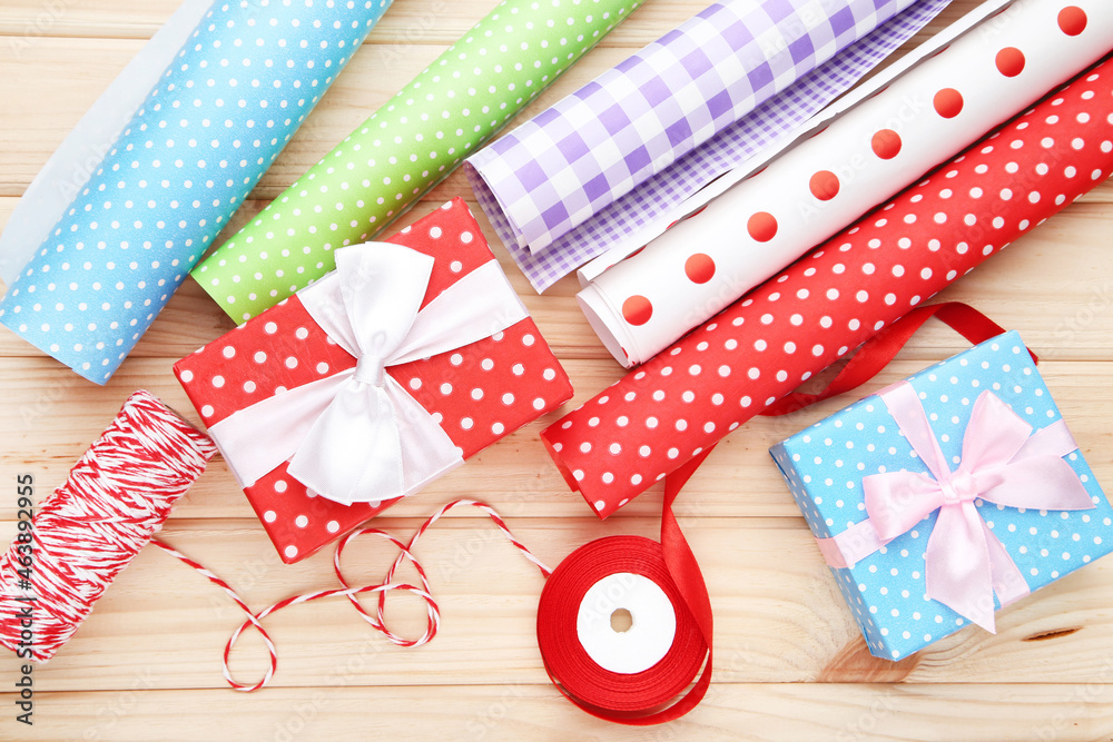 Obraz premium Rolls of craft papers with gift boxes, ribbon and rope on wooden background