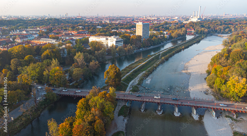 Fototapeta premium Aerial view of Isar river flowing into Munich and Thalkirchen bridge with cars in a beautiful autumn landscape