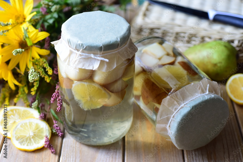 Preparation for winter: sweet compote of pears in glass jars on a white table